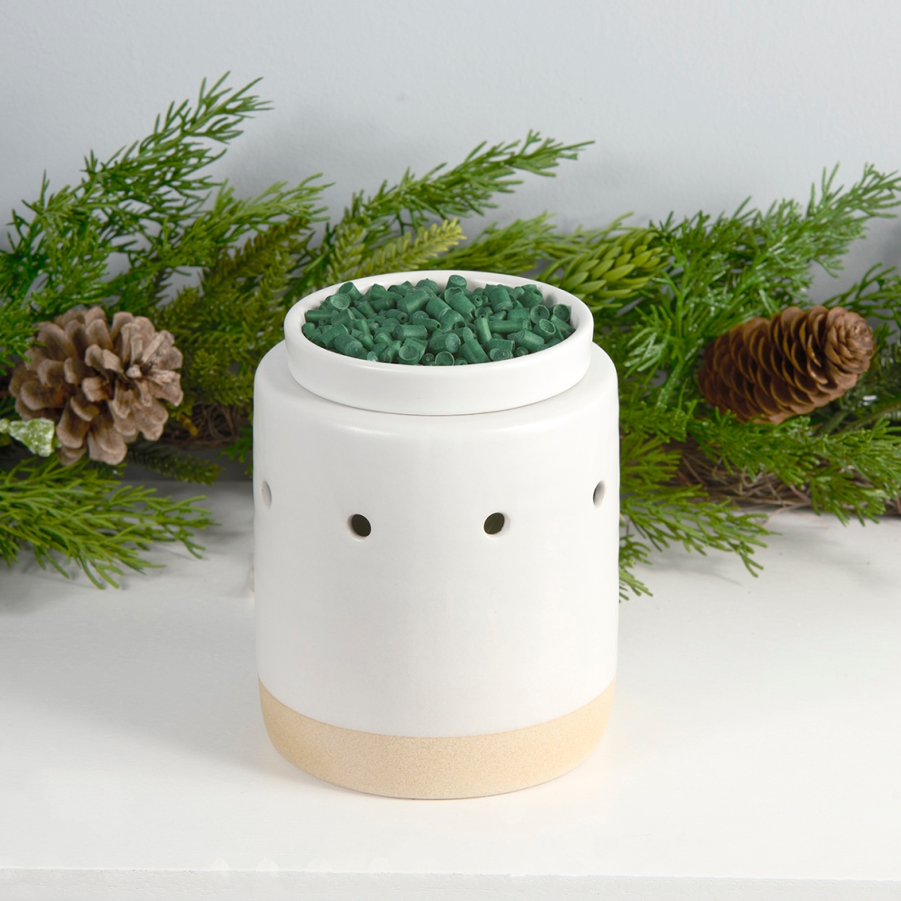 Scentsicles fragrance granules in a ceramic warmer, releasing the natural scent of a fresh-cut Christmas tree to enhance home decor during the holiday season.