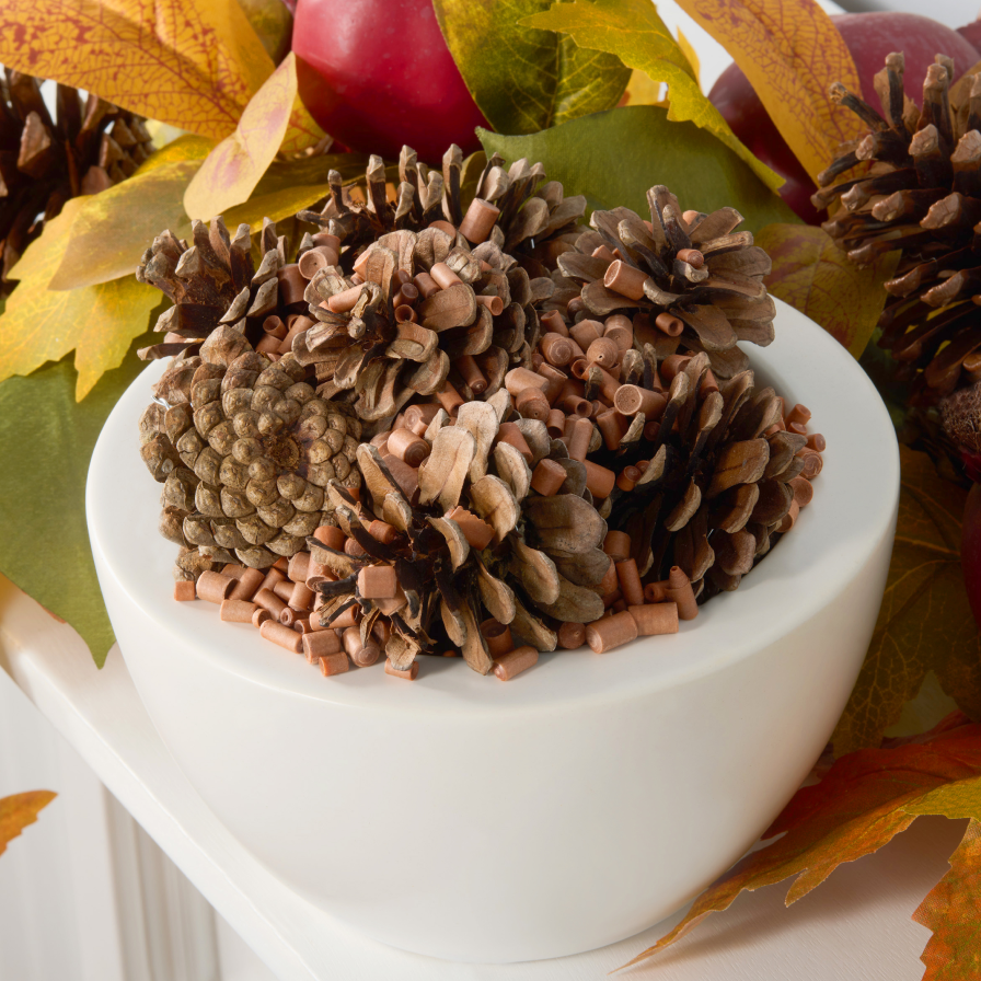 Pinecones mixed with Scentsicles fragrance granules in a white bowl, creating a festive autumn centerpiece with a warm, spiced pine scent.