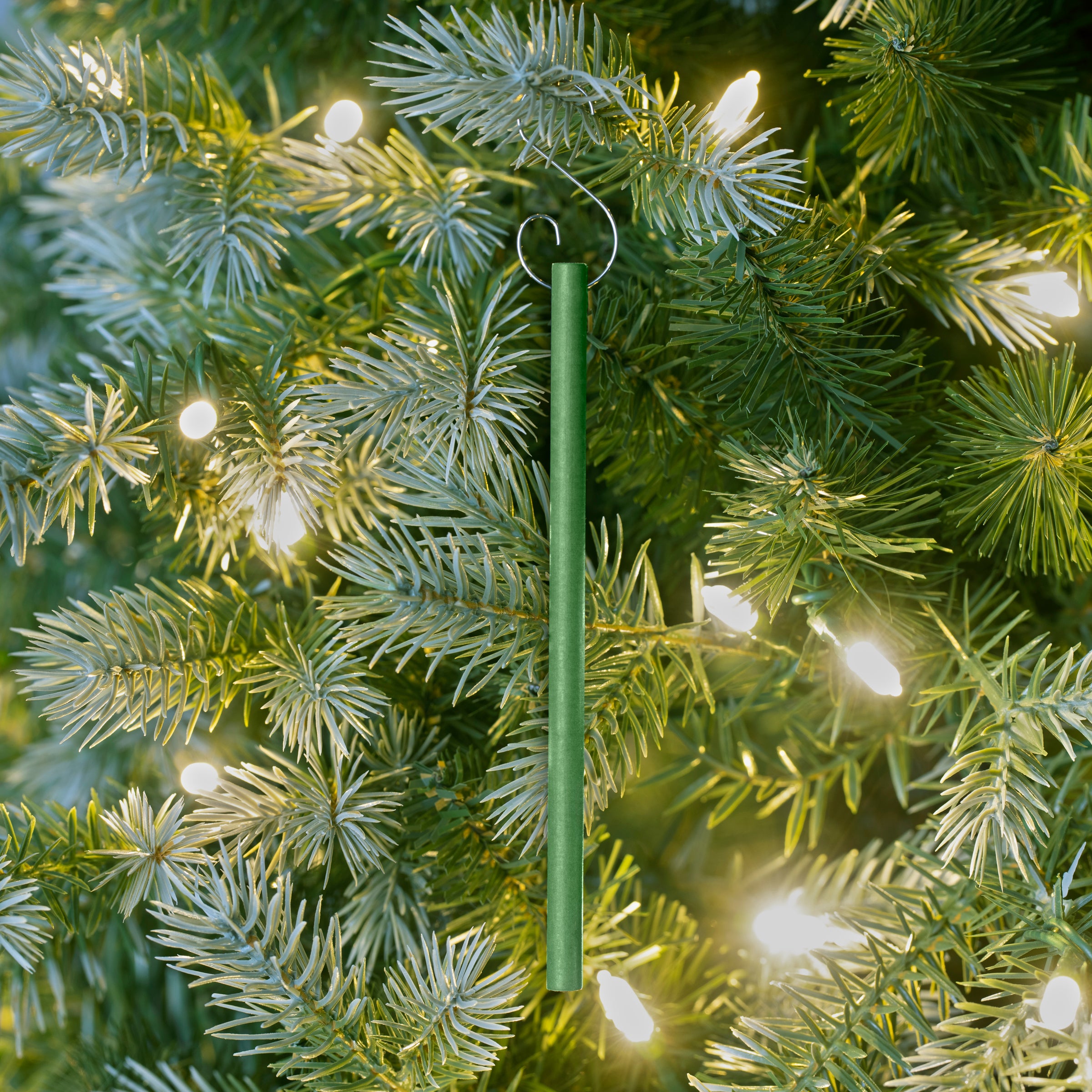 Scentsicles scented ornament stick hanging on a lit artificial Christmas tree, infusing the room with the fresh and natural fragrance of pine.