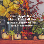 Image featuring a cozy fall-themed display with decorative pumpkins, vibrant autumn foliage, and glass jars filled with seasonal elements. The text overlay highlights the product's scent and safety features: 'Crisp Apple Scent. Flame Free Fall Fun. Sprinkle or display. No leaks, spills, or open flames.