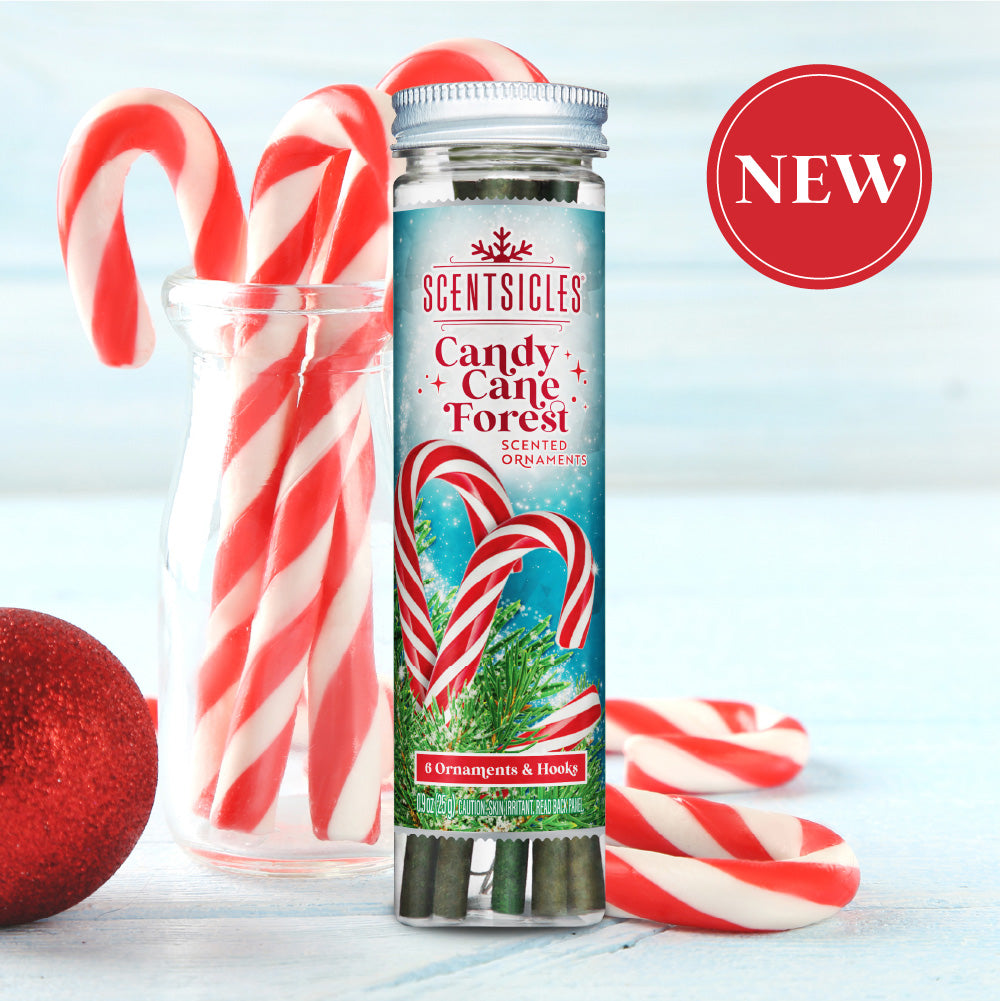 Scentsicles 'Candy Cane Forest' scented ornaments tube placed in front of a festive display with red and white candy canes in a glass jar, alongside a red ornament ball. The product label features candy canes and evergreen branches, with a 'NEW' badge in the upper right corner.