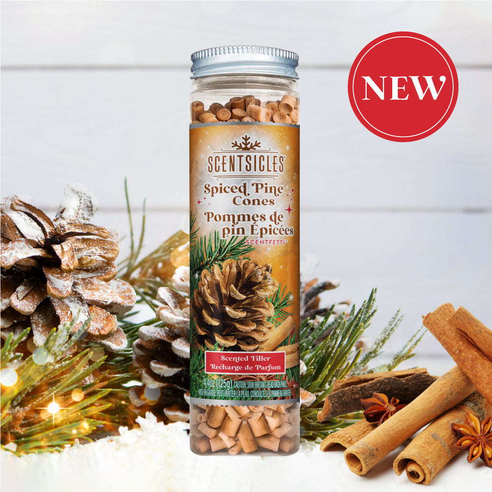 Image of Scentsicles 'Spiced Pine Cones' scented filler displayed in front of a festive background featuring snow-dusted pine cones, cinnamon sticks, and a 'NEW' badge in the upper right corner, highlighting the seasonal and aromatic essence of the product.