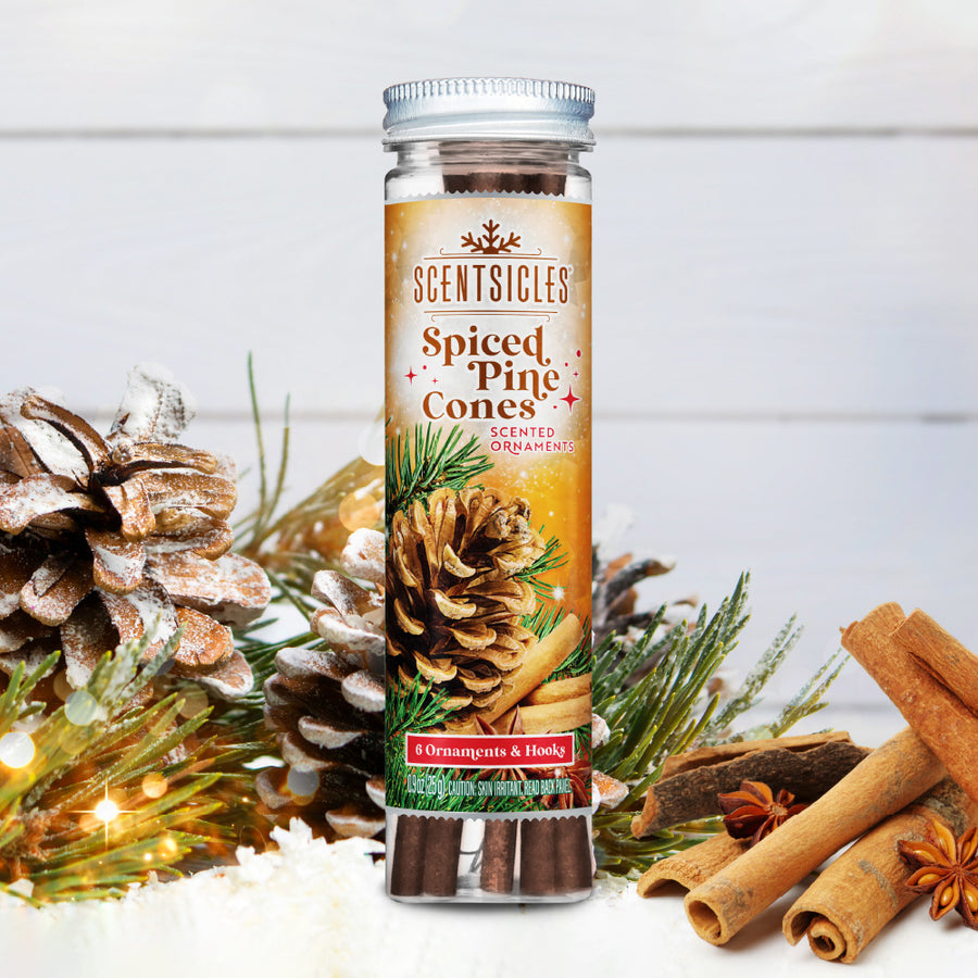 Scentsicles Spiced Pine Cones scented ornaments bottle with six ornaments and hooks, placed among snow-dusted pinecones, cinnamon sticks, and holiday greenery, capturing the warm and festive fragrance of the season.