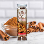 Scentsicles Two Dashes of Cinnamon scented ornaments bottle with six ornaments and hooks, placed in front of a bowl of cinnamon powder and cinnamon sticks, capturing the warm and spicy fragrance of the holiday season.