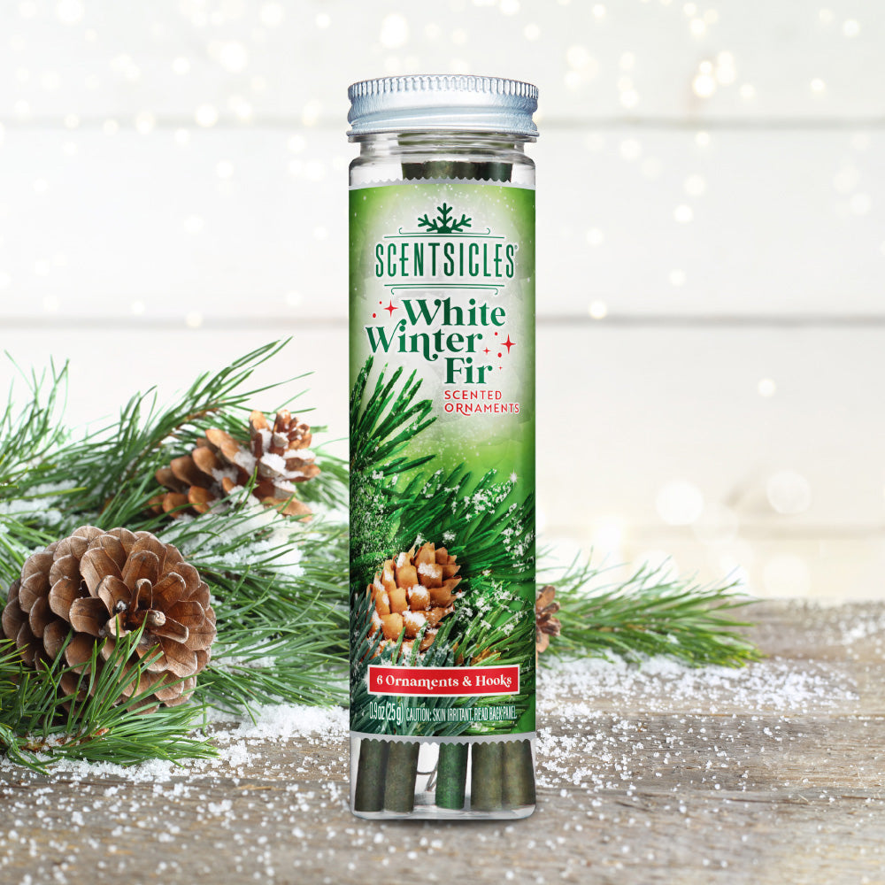 Scentsicles White Winter Fir scented ornaments bottle with six ornaments and hooks, placed on a snowy surface with pine branches and pinecones in the background, evoking the fresh scent of a winter forest.